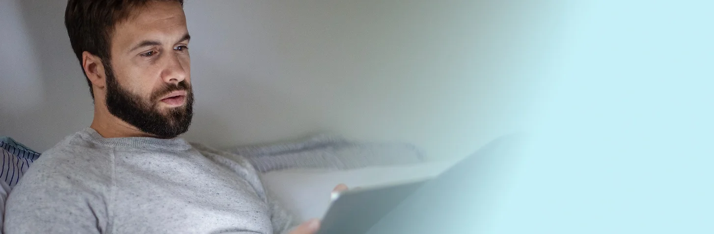 Man sitting on a bed appearing tired