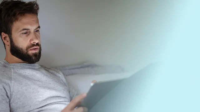 Man sitting on a bed appearing tired